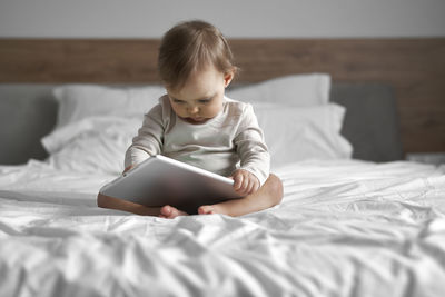 Portrait of boy using mobile phone while lying on bed at home