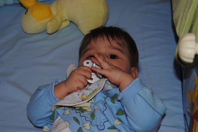 Portrait of cute baby boy sucking pacifier in crib at home