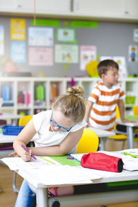 Girl writing in paper at kindergarten