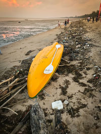 Yellow boat on beach against sky during sunset