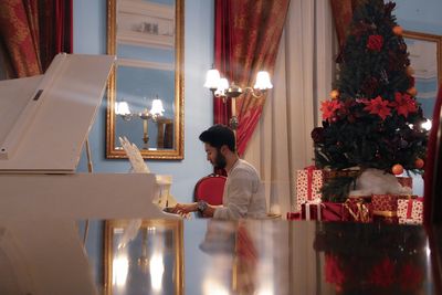 Side view of man playing piano at home