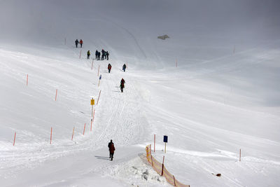 People skiing on snow covered landscape