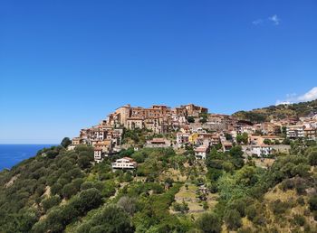 Townscape by sea against clear blue sky