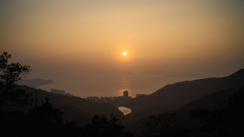 Scenic view of silhouette mountains against orange sky