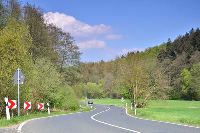 Road by trees against sky