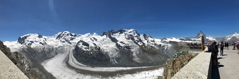 Panoramic view of snowcapped mountains against blue sky