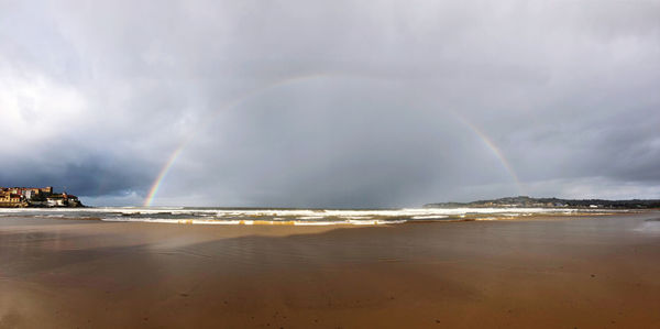 Scenic view of sea against rainbow in sky