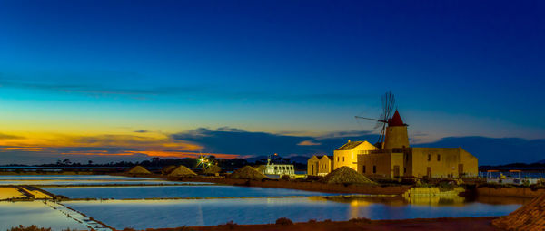 Buildings by salt flats against sky during sunset