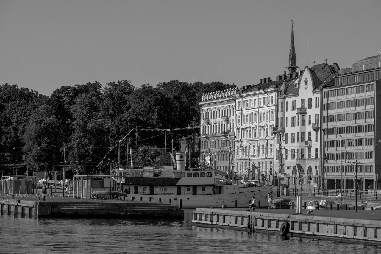 architecture, water, built structure, building exterior, black and white, cityscape, monochrome, city, monochrome photography, sky, waterway, nature, urban area, tree, nautical vessel, building, transportation, dock, river, mode of transportation, vehicle, travel destinations, skyline, no people, clear sky, waterfront, travel, ship, boat, plant, outdoors, day, tourism