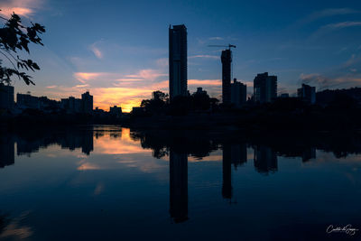 Reflection of buildings in lake against sky during sunset