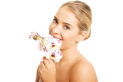 Close-up of shirtless woman with flowers against white background