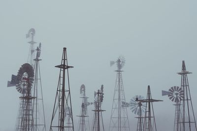 American-style windmills against sky during foggy weather