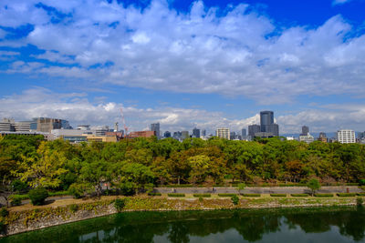 Scenic view of river by buildings against sky