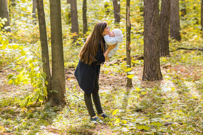 Woman standing by tree on field in forest