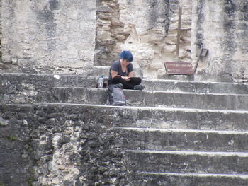 Man sitting on staircase against wall