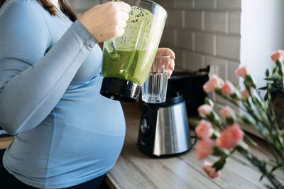 Green smoothies recipes for pregnancy and postpartum, prenatal nutrition. pregnant woman preparing