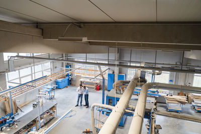 Two carpenters standing and talking in production hall