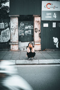 Woman sitting on entrance of building