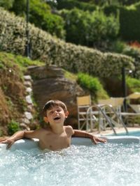 Cheerful shirtless boy in swimming pool