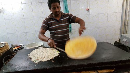 Tilt shot of chef flipping thosai at commercial kitchen