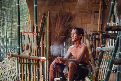 Smiling young woman sitting on chair outdoors