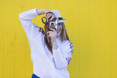 Portrait of young woman with yellow camera