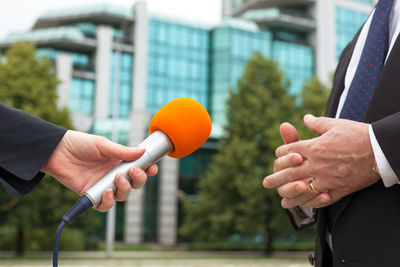 Journalist holding microphone while taking interview of businessman