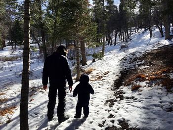 Rear view of man walking on snow covered forest