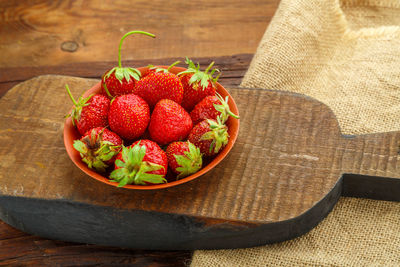 Ripe strawberries in a plate on a wooden table on a wooden board. horizontal photo