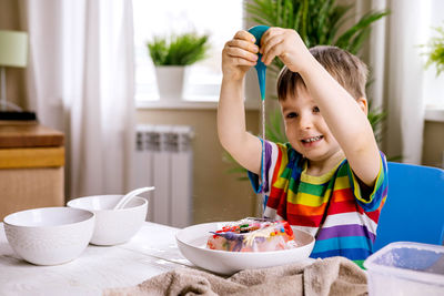 Smiling boy pouring water on frozen toys at home