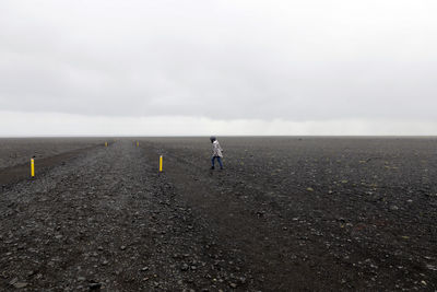 Side view of woman walking on field against sky