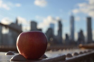 Close-up of apple with city skyline