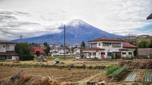 Houses on field by buildings against sky