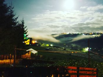 Illuminated street light against cloudy sky