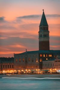 Illuminated building against sky during sunset