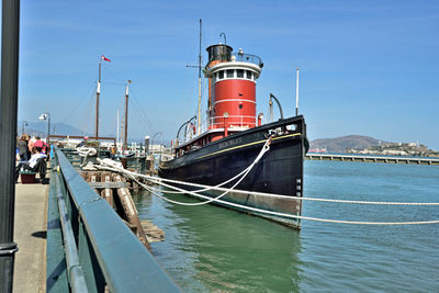 Ship moored in water against blue sky