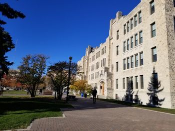 Street amidst buildings against clear blue sky