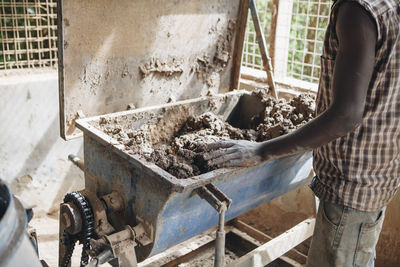 Midsection of worker kneading clay in workshop