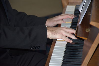 Midsection of man playing piano