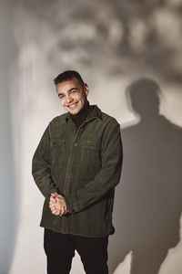 Portrait of smiling man with hands clasped over white background