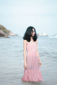 Woman standing on pink water with arms raised in background