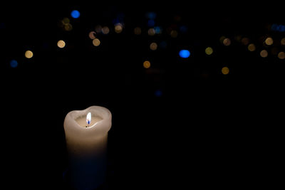 Close-up of lit candle against black background