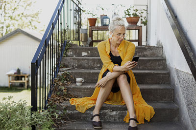 Woman sitting on steps and using cell phone