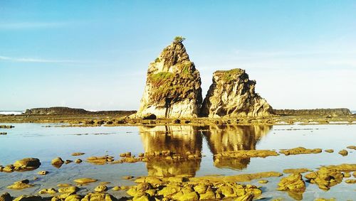 Rock formation on beach against sky