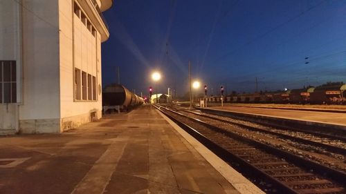 Illuminated railroad tracks by buildings in city at night