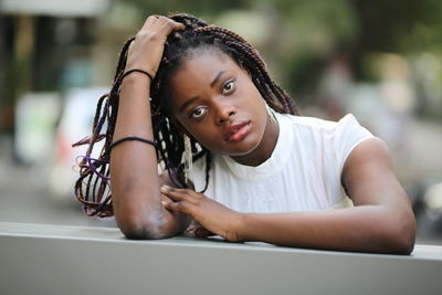 Portrait of young woman with hand in hair outdoors