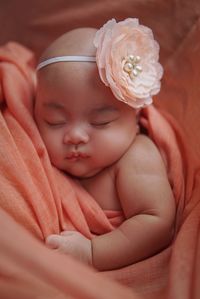 Close-up of cute baby girl lying on bed at home