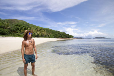 Full length of shirtless man standing on beach