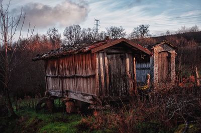 Old wooden house on field against sky