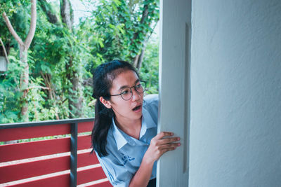 Shocked young woman peeking at balcony